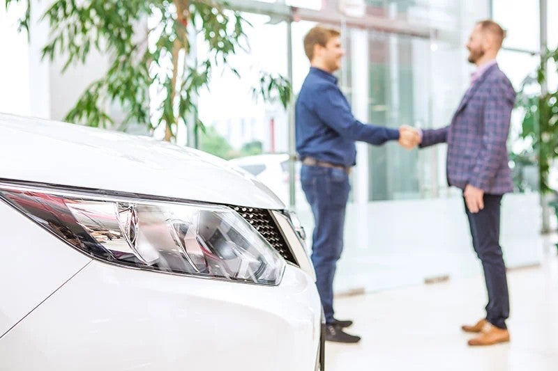 Two people shaking hands inside a car dealership