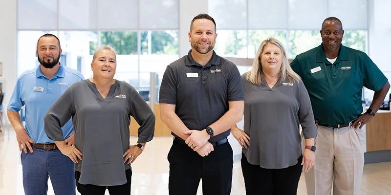Group of employees standing together inside a car dealership
